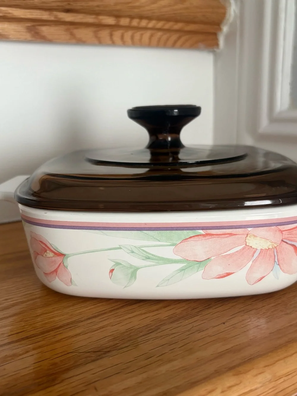 A vintage Corning Ware casserole dish in the Peony Floral pattern with lid